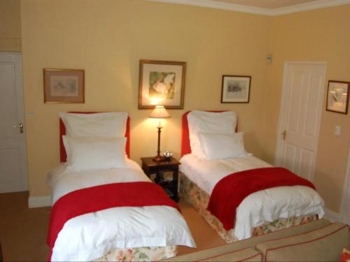 a bedroom with two beds with red and white pillows at Watersmeet cottages in Dullstroom