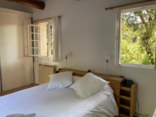 - une chambre avec un lit doté de draps blancs et 2 fenêtres dans l'établissement 757 Chemin du Vialat, à Boissières