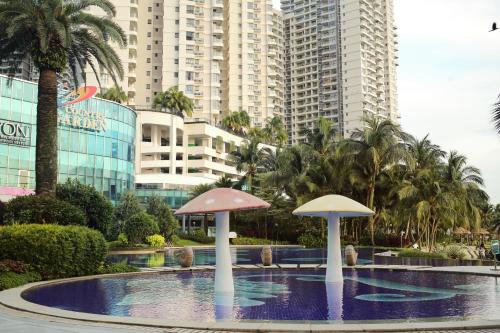 deux parasols dans une piscine en face de certains bâtiments dans l'établissement Kid-Loving Poolside Haven - 2BR - Netflix - Games, à Johor Bahru