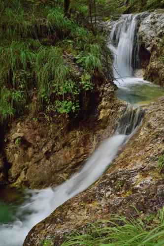 a waterfall on the side of a mountain next to a creek at Apartment Sotočje in Dolenja Trebuša