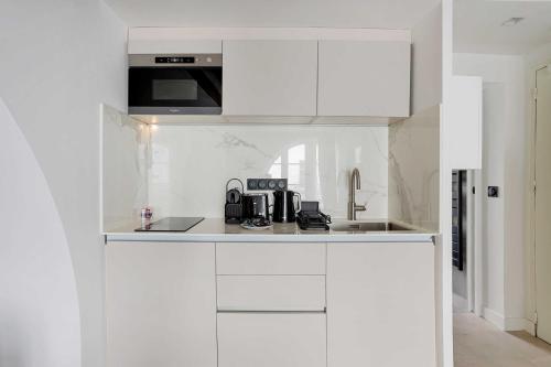 une cuisine blanche avec des armoires blanches et un micro-ondes dans l'établissement Cozy apartment - 1BR-4P - Les Halles, à Paris