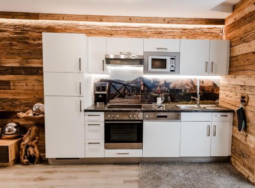 a kitchen with white cabinets and stainless steel appliances at Chalet mit Sauna direkt an der Mittelstation Panoramabahn Kitzbühel in Mittersill