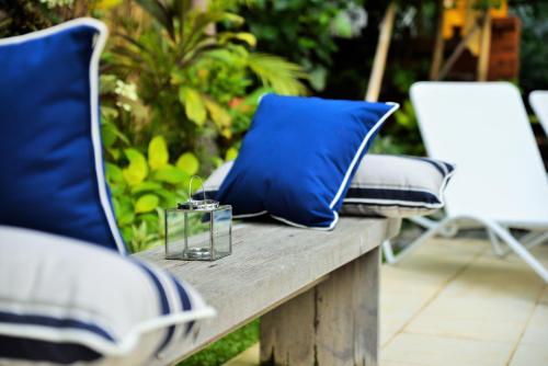 a wooden bench with blue pillows and two chairs at Lata Lama in Lovina