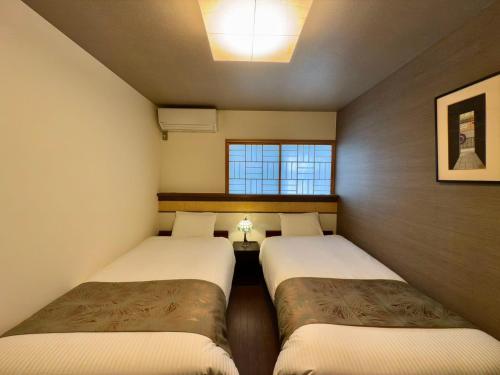 two twin beds in a small room with a window at 古月居 Koduki House京都四条 in Kyoto