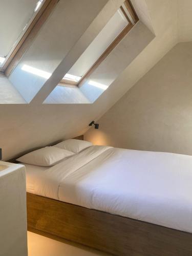 a bedroom with a white bed with a skylight at Edville Studio in Ghent