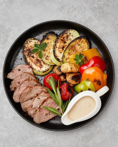 a plate of food with meat and vegetables on a table at Yerevan Place Hotel in Yerevan