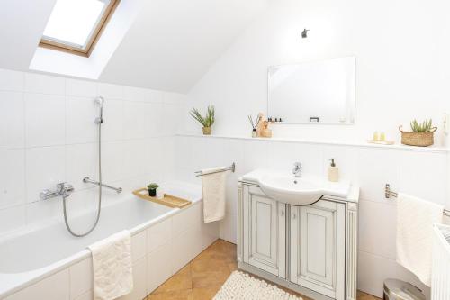 a white bathroom with a sink and a bath tub at Aquilo Apartmanok in Tihany