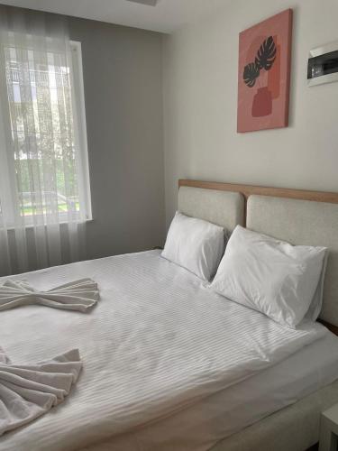 a bed with white sheets and pillows and a window at Sorta Hotel in Antalya