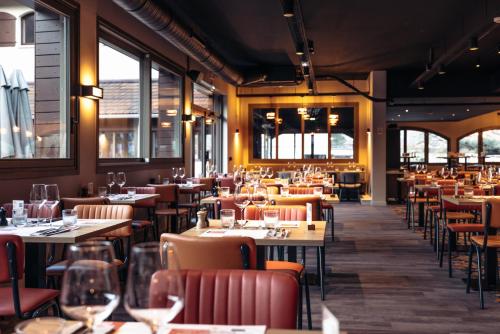 a restaurant with tables and chairs and windows at Hotel Base Camp Lodge - Albertville in Albertville