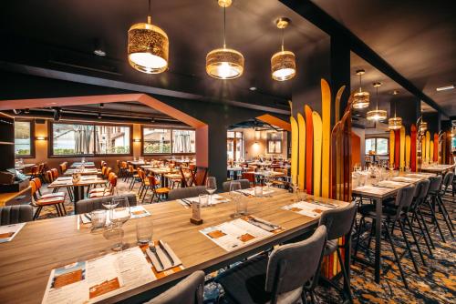 a dining room with tables and chairs and surfboards at Hotel Base Camp Lodge - Albertville in Albertville