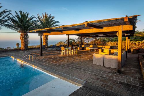 una piscina con pérgola, mesa y sillas en Residenza Khaddiuggia, en Pantelleria