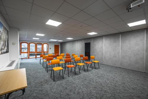 a conference room with orange chairs and tables in it at Hotel Base Camp Lodge - Albertville in Albertville