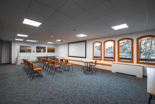 a conference room with tables and chairs and a screen at Hotel Base Camp Lodge - Albertville in Albertville