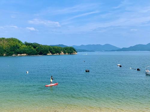 a person standing on a kayak in a large body of water at Orange open-air bath of East Villa-winter only- in Onomichi