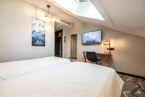 two beds in a room with a desk and a tv at Hotel Base Camp Lodge - Albertville in Albertville