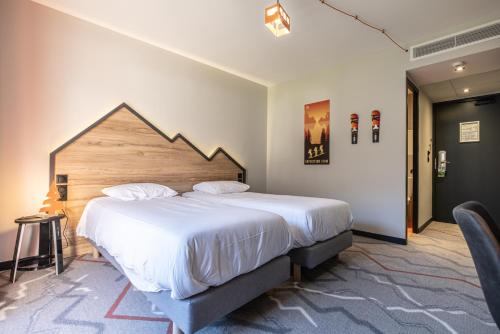 a bedroom with a large bed with a wooden headboard at Hotel Base Camp Lodge - Albertville in Albertville