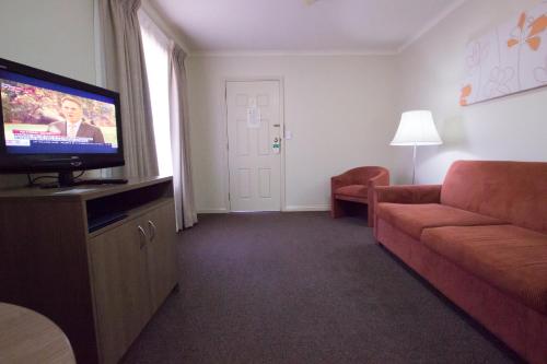 a living room with a couch and a flat screen tv at Old Willyama Motor Inn in Broken Hill