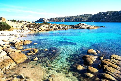 a rocky beach with blue water and rocks at Mistral in Capo Testa