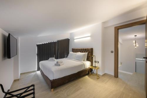 a bedroom with a large white bed and a television at Cens Platinum Luxury Suites in Ioannina