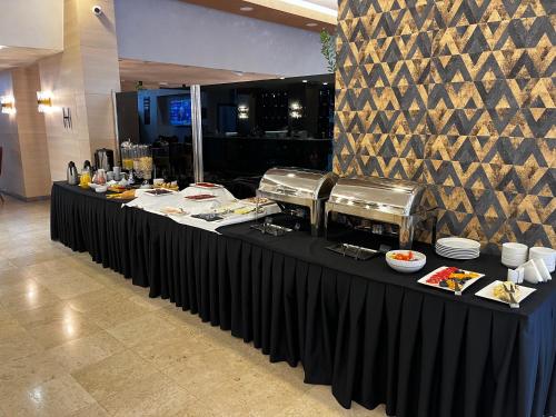 a long black table with plates of food on it at Hotel Monogram Park in Ruma