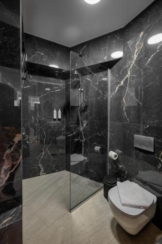 a bathroom with a glass shower with a toilet at Cens Platinum Luxury Suites in Ioannina