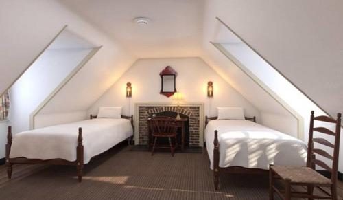 a attic bedroom with two beds and a fireplace at Colonial Houses, an official Colonial Williamsburg Hotel in Williamsburg