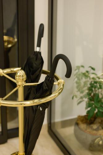 a black umbrella in a gold stand next to a mirror at Cens Platinum Luxury Suites in Ioannina