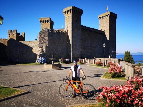 a man standing with a bike in front of a castle at Agriturismo Buonasera in Bagnoregio