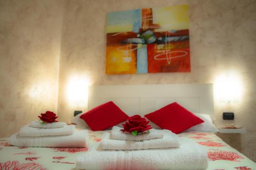 Una cama con almohadas rojas y flores rojas. en Corallia Apartment, en Siracusa
