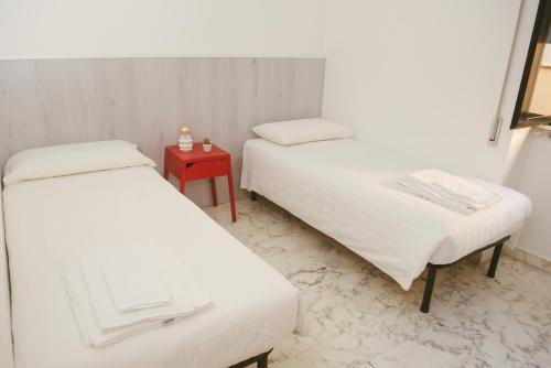 two beds in a room with a red table at B&B Boteroom in Cassino