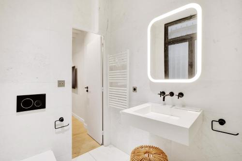 une salle de bain blanche avec un lavabo et un miroir dans l'établissement Pick A Flat's Apartment in Palais Royal - Rue de Richelieu, à Paris