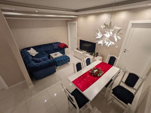 a living room with a table and a blue couch at Apartman Cookie Kolačić blizu aerodroma Nikola Tesla in Dobanovci