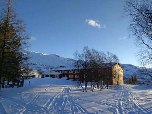 a snow covered road with a building in the distance at Vatnahalsen Høyfjellshotell in Myrdal