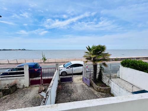 a white car parked next to a fence next to the ocean at Villa Océan- Vue imprenable sur la côte Atlantique in Fouras
