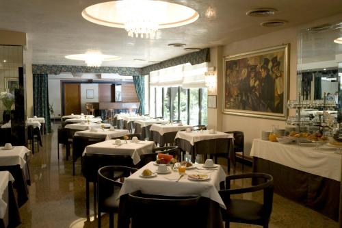 a dining room with tables and chairs with white table cloth at Hotel Leonardo Da Vinci in Sassari