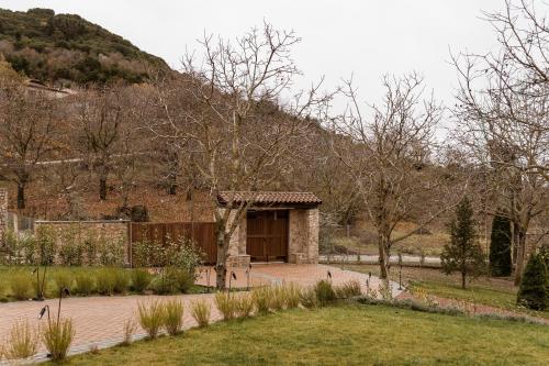 a stone building with a door in a garden at HERMEA Grand Mountain Villa & Spa in Feneos