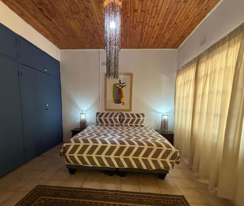 a bedroom with a bed and a chandelier at The Seed Pod Guesthouse in Modimolle