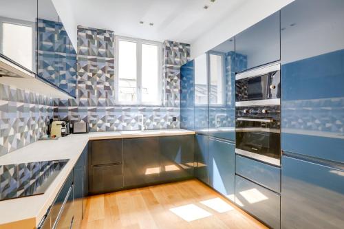 Il comprend une cuisine avec des murs bleus et blancs et du parquet. dans l'établissement Sublime appartement Paris 4Br-12P, à Paris