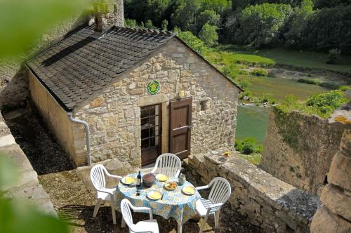 a table and chairs in front of a stone house at Gite de pougnadoires in Sainte-Énimie