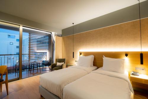 a hotel room with two beds and a balcony at Magnes Hotel in Volos