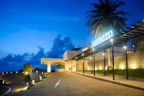 a building with a palm tree in the night at Infinito Hotel and Spa in Shirahama