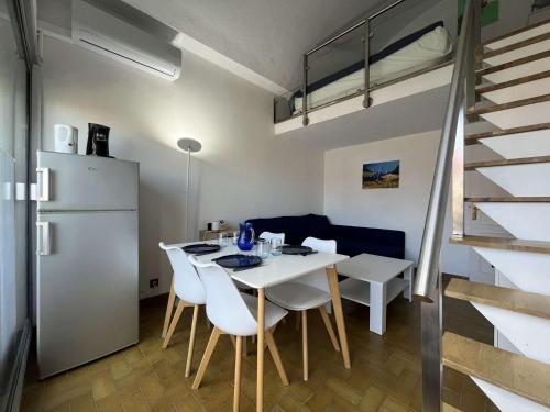une cuisine et une salle à manger avec une table et des chaises blanches dans l'établissement Appartement studio mezzanine - Gruissan GN140-039, à Gruissan
