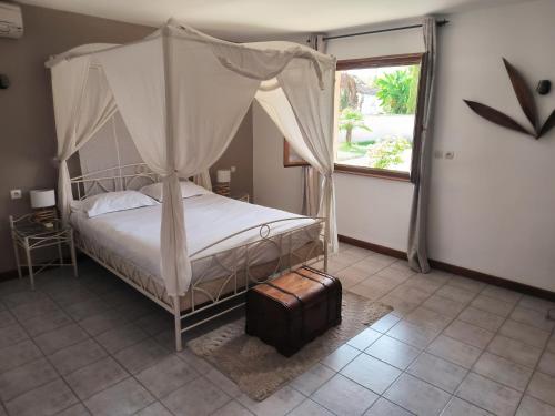 une chambre avec un lit à baldaquin et une fenêtre dans l'établissement Logis Hôtel -Spa-Restaurant Le Saint Antoine, à Lamarche-sur-Saône