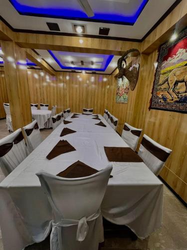 a long table in a room with white tables and chairs at Heaven Hotel Skardu in Skardu