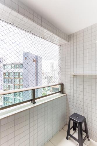 a stool in a white tiled bathroom with a window at Beach Class Santa Maria by Easy Home in Recife