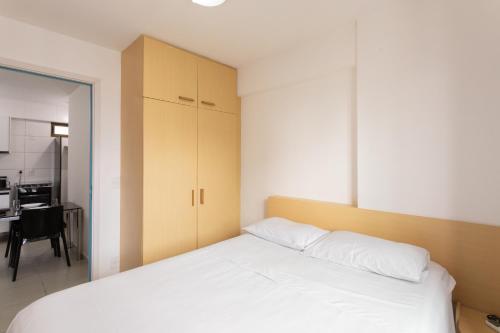 a bedroom with a white bed and a kitchen at Beach Class Santa Maria by Easy Home in Recife
