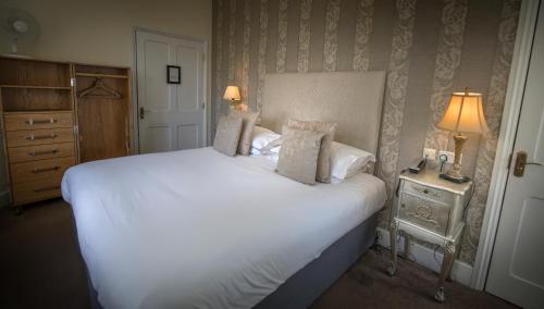 a bedroom with a large white bed and a night stand at Château Rhianfa in Menai Bridge