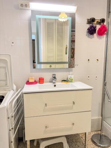 une salle de bain blanche avec un lavabo et un miroir dans l'établissement La Caze - Idéal couple de curistes - 40 m2, à Balaruc-les-Bains