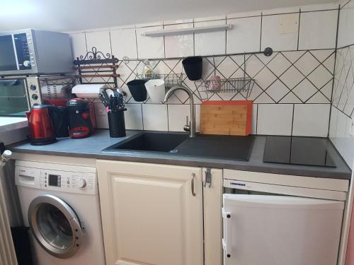 une cuisine avec un évier et une machine à laver dans l'établissement Charmante maisonnette de caractère, à Châteauroux