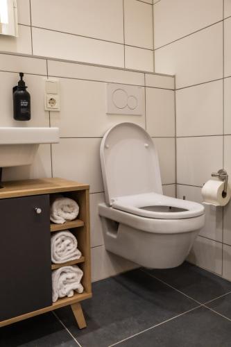 a bathroom with a toilet and a shelf with towels at HLN APARTMENTS Am Bahnhof in Saarbrücken